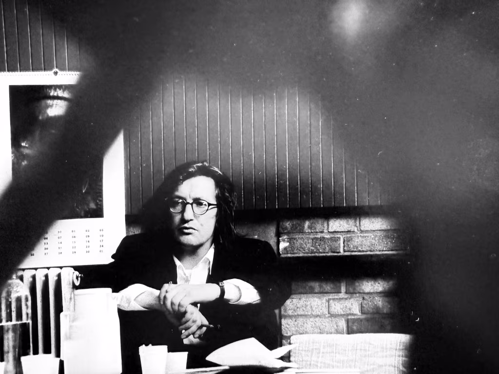 Zwart-witfoto binnenruimte met persoon en bril bij open haard en muurkalender, thema toneelregisseur johan doesburg